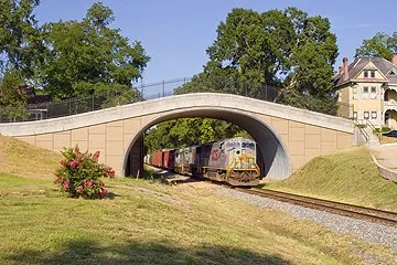 Deep corrugated structural plate arch carrying rail line over transportation corridor