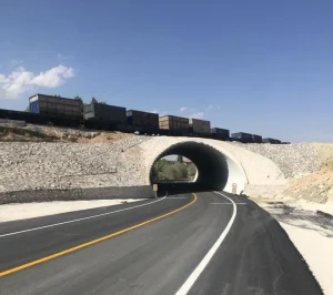 Completed structural plate railway underpass carrying rail traffic above a newly reconstructed roadway.